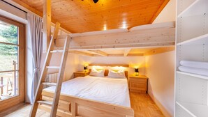 Une chambre à coucher en bois avec une échelle, un lit, des lampes de chevet et une vue par la fenêtre.