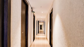 A long, narrow hallway with doors on both sides, leading to a bright room at the end. - Lake View - by Brill Rooms (Kolkata)