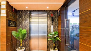 An elevator with a geometric patterned wall, two potted plants, and a wooden finish on the walls. - Lake View - by Brill Rooms (Kolkata)