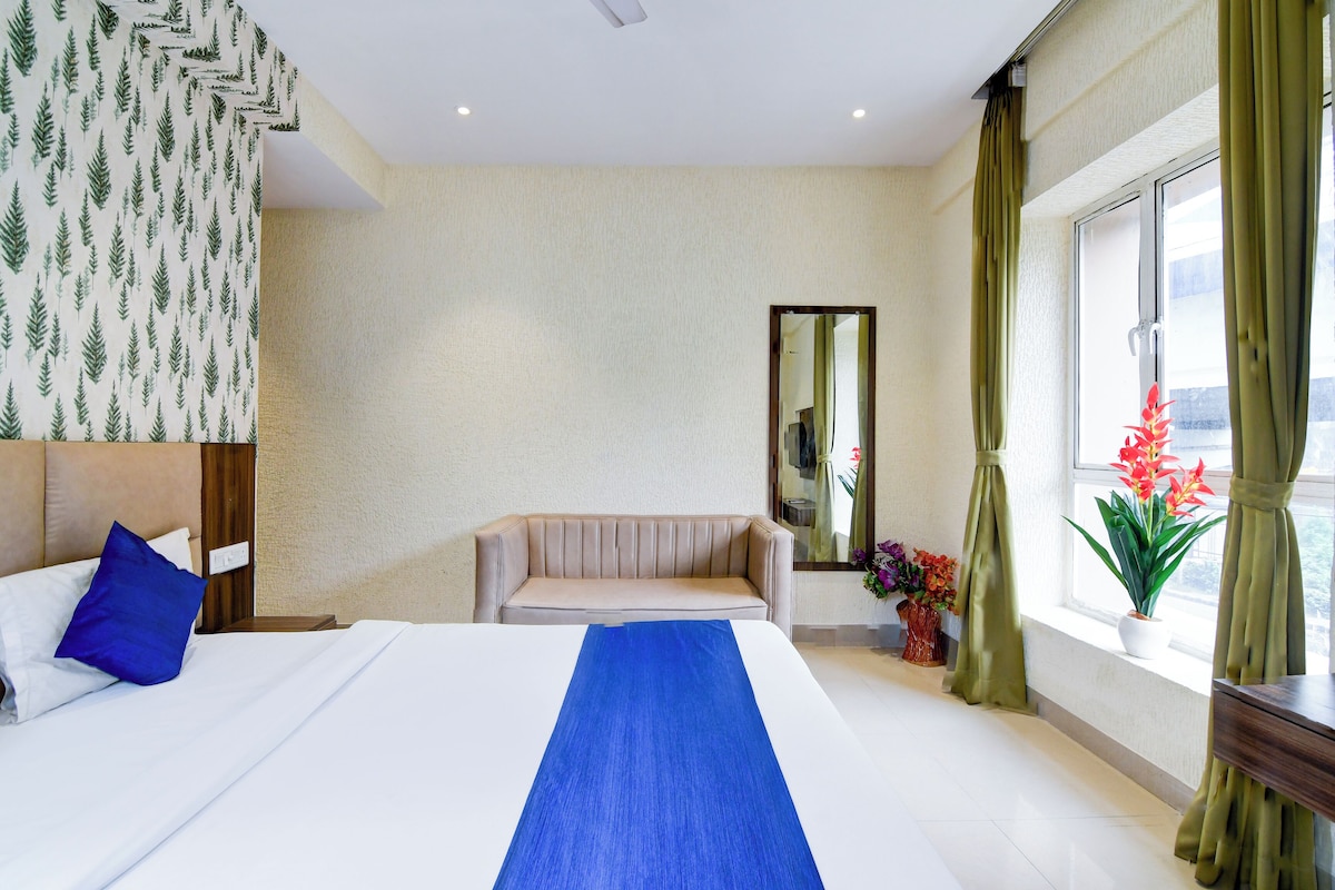 Une chambre d’hôtel avec un lit, un canapé, un miroir, une fenêtre avec des rideaux et une vue sur l’extérieur.