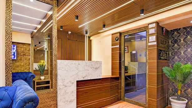 A reception area with a marble counter, wooden paneling, and a blue sofa. - Lake View - by Brill Rooms (Kolkata)