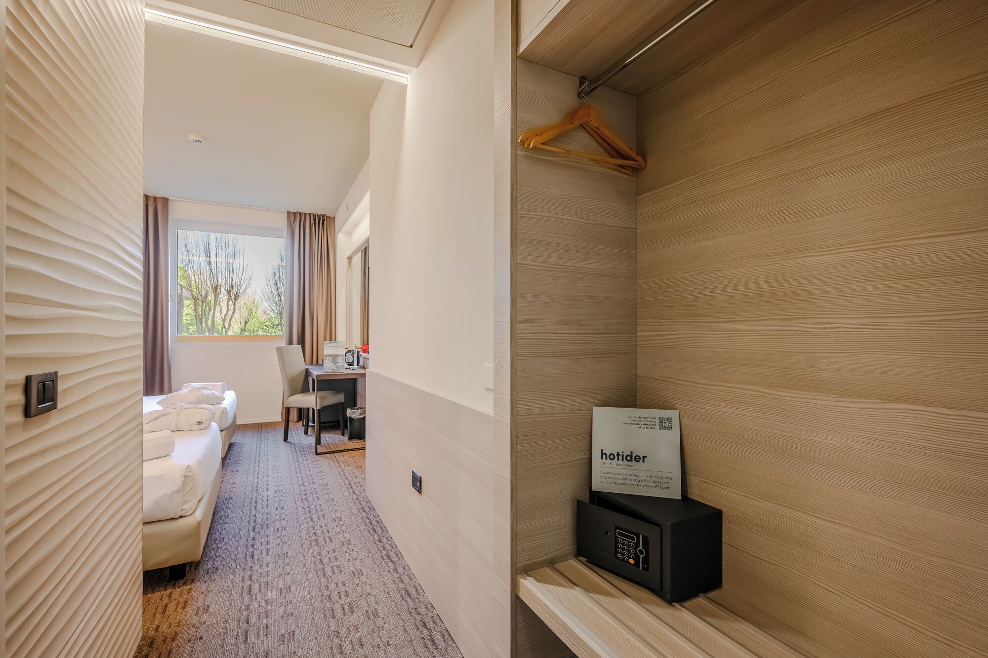 Ein Hotelzimmer mit Bett, Schreibtisch und Duschbereich.