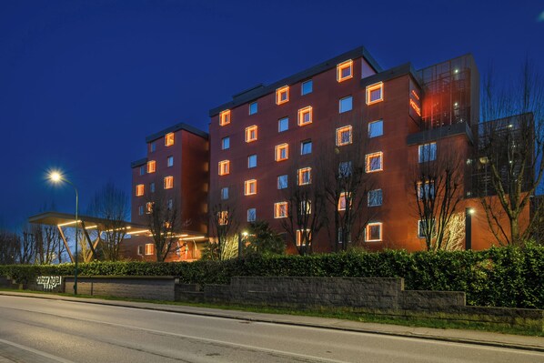 A modern hotel with multiple floors, a well-lit facade, and a clear view of the street in front. - Hotiday Venezia Marco Polo (Mestre)