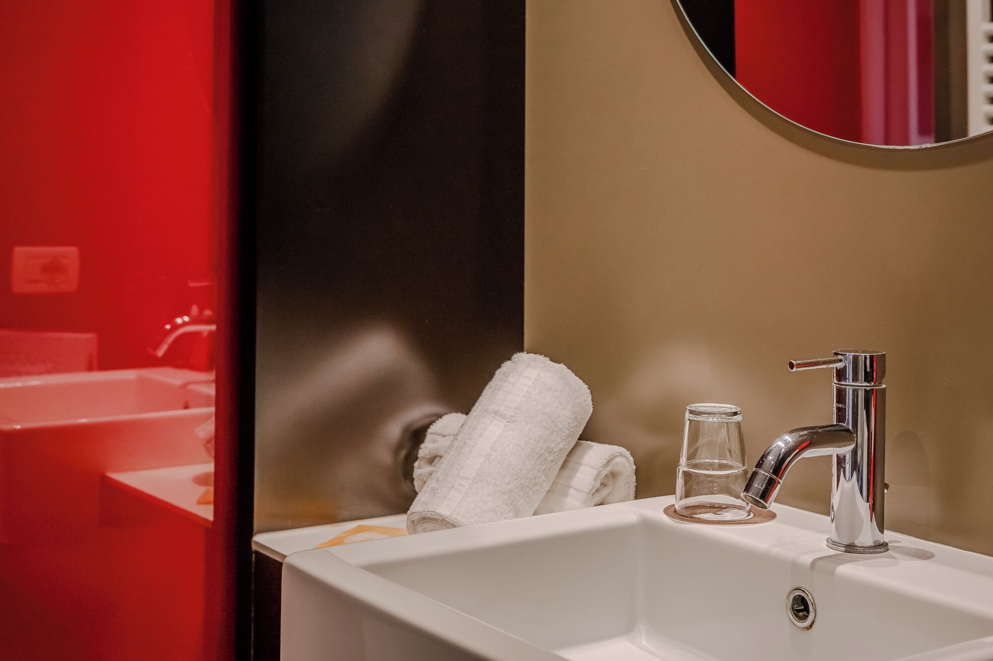 A bathroom with a white sink, a mirror, and a towel.