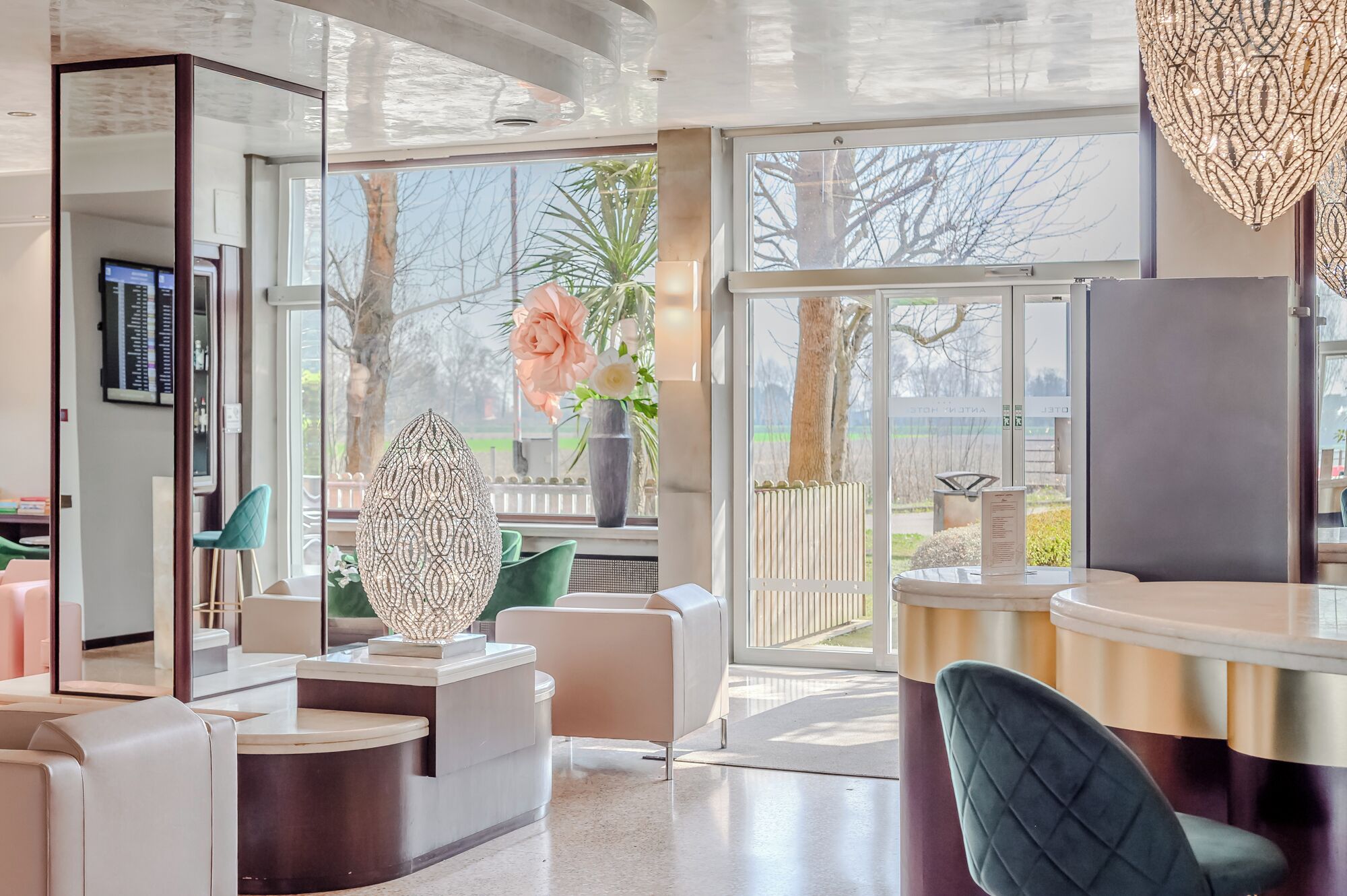A modern hair salon with a large mirror, a reception desk, and a view of the outdoors.