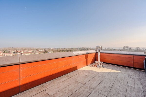 A rooftop terrace with a wooden floor, a telescope, and a view of a residential area. - Hotiday Venezia Marco Polo (Mestre)