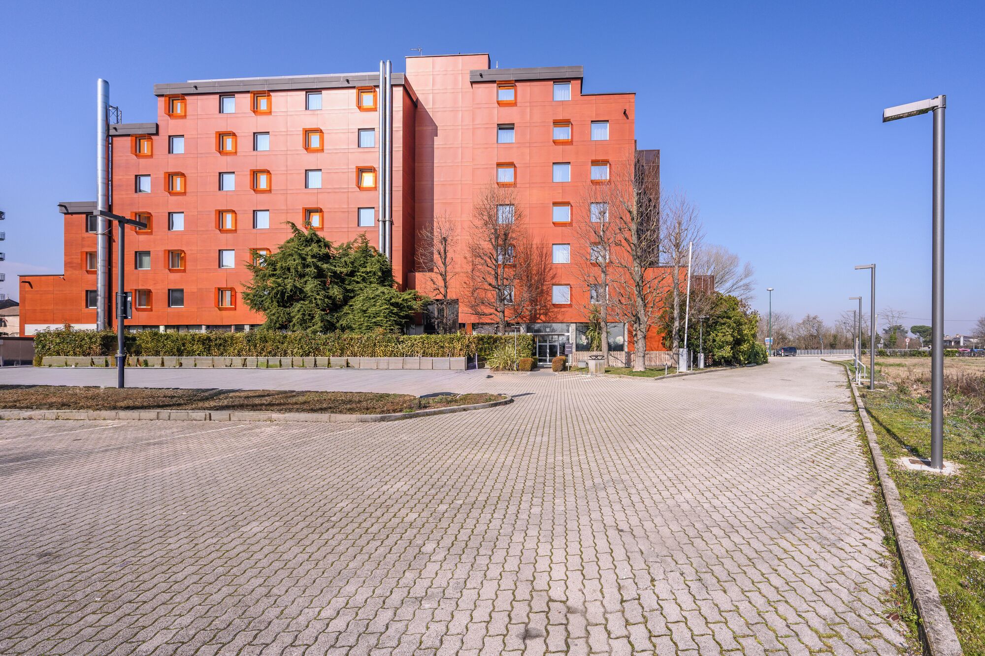 A modern red building with multiple windows and a paved entrance area.