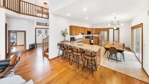 Una cocina amplia con una isla central, taburetes de madera y una mesa de comedor.