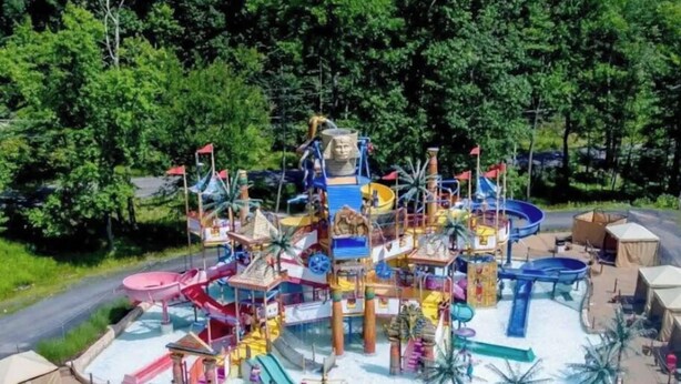 Un parque acuático con múltiples toboganes y piscinas, rodeado de árboles.