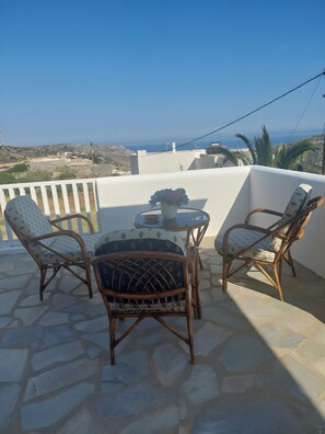 A terrace with wicker chairs, a table, and a vase of flowers. - Xanthi House Sikinos (Σίκινος)