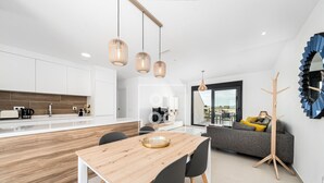 A modern kitchen with white cabinets, a wooden dining table, and pendant lights. - Golf Vista Penthouse, golf views, rooftop dining - by Oyoostays (Pilar de la Horadada)