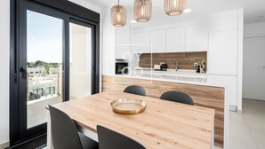 A modern kitchen with white cabinets, a wooden countertop, and three pendant lights. - Golf Vista Penthouse, golf views, rooftop dining - by Oyoostays (Pilar de la Horadada)