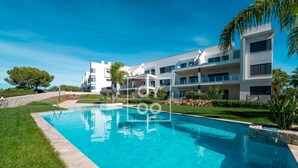 A modern hotel with a swimming pool, multiple balconies, and a well-maintained lawn. - Golf Vista Penthouse, golf views, rooftop dining - by Oyoostays (Pilar de la Horadada)