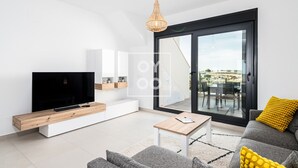 A modern living room with a flat-screen TV, a wooden coffee table, a grey sofa with yellow cushions, and a large sliding glass door leading to an outdoor area. - Golf Vista Penthouse, golf views, rooftop dining - by Oyoostays (Pilar de la Horadada)