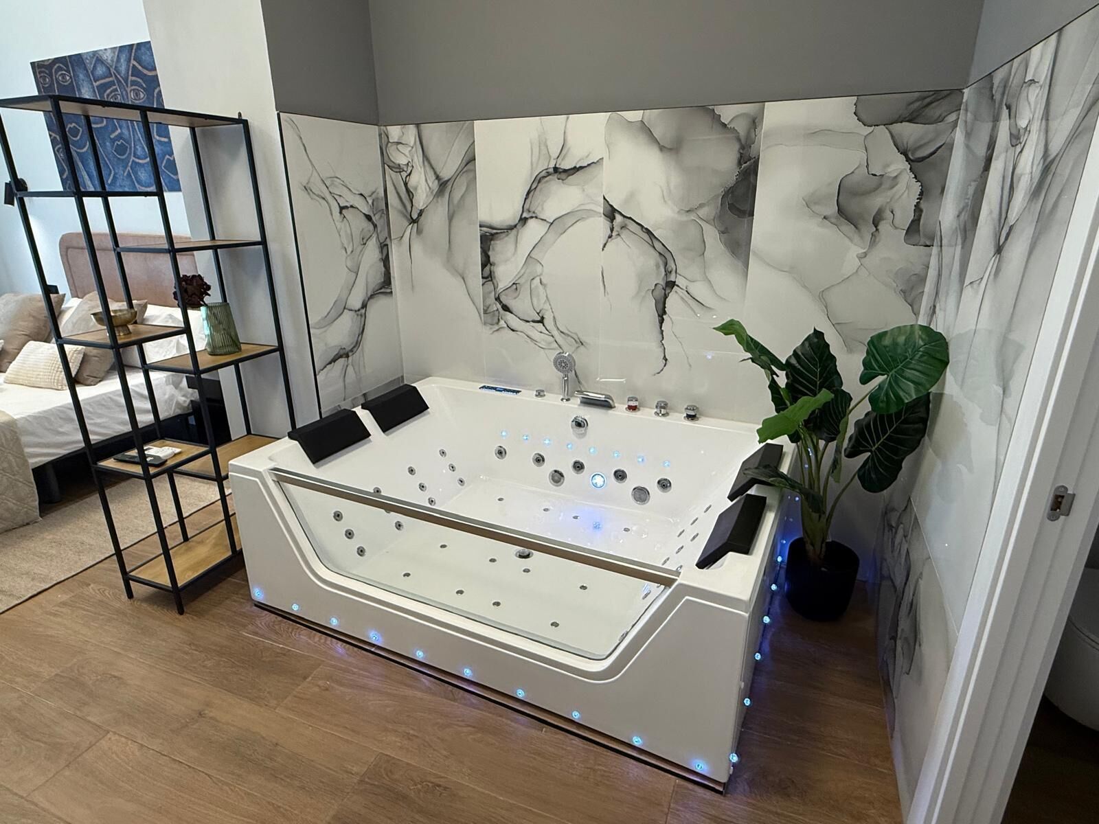 Un baño moderno con una bañera independiente, pared de mármol y un estante pequeño con artículos de aseo.