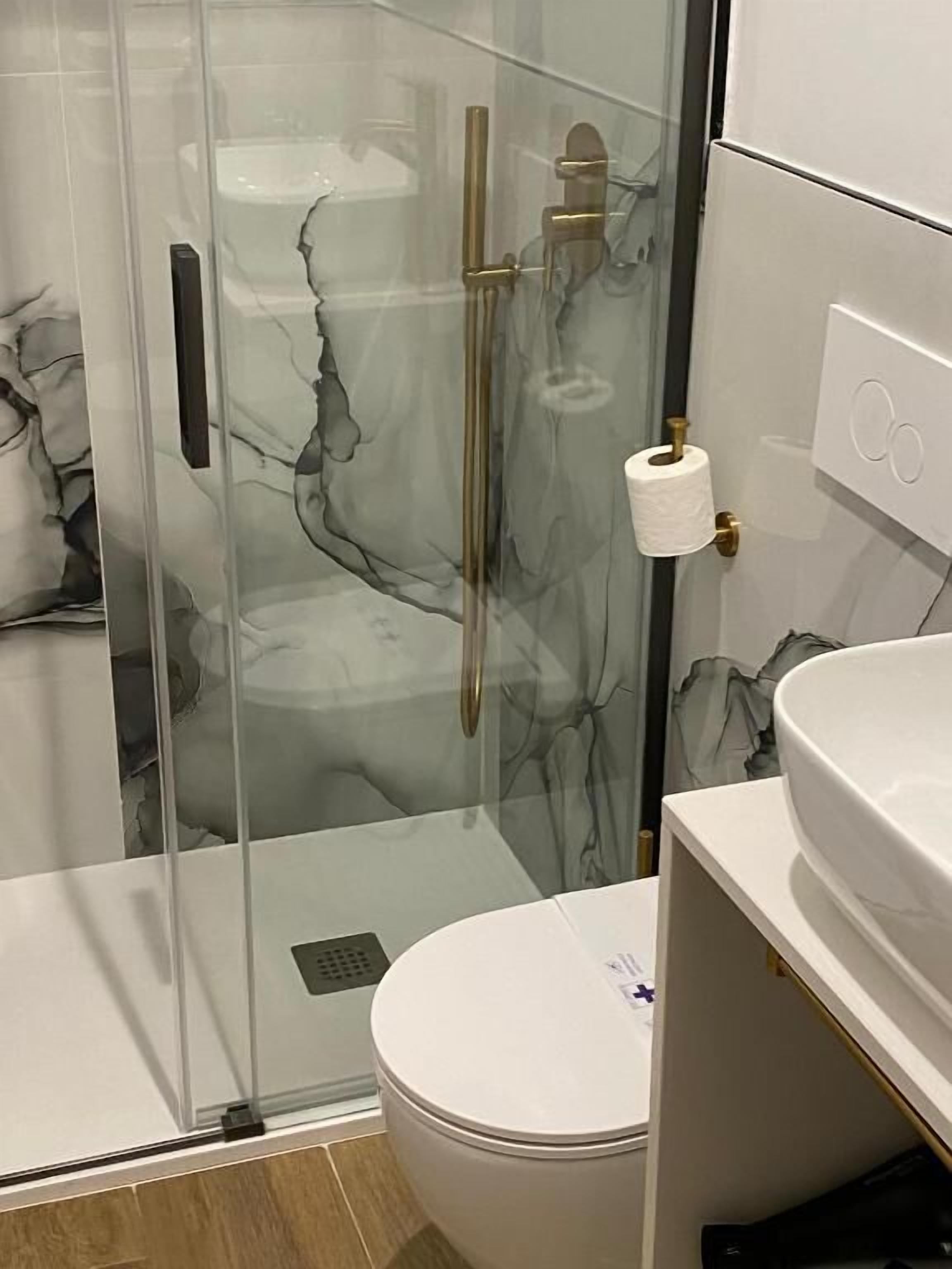 Un baño moderno con ducha envuelta en vidrio, inodoro y lavabo.