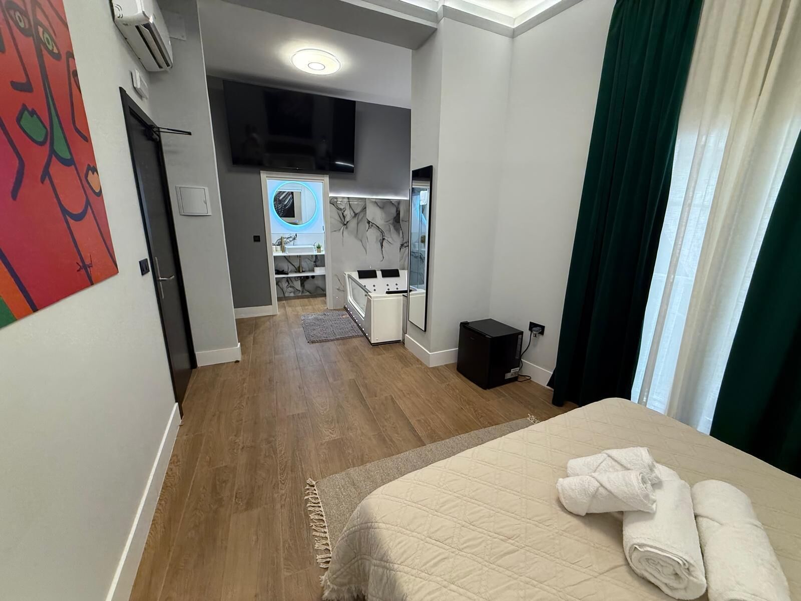 Et hotelværelse med seng, fjernsyn, et lille tekøkken og badeværelse.