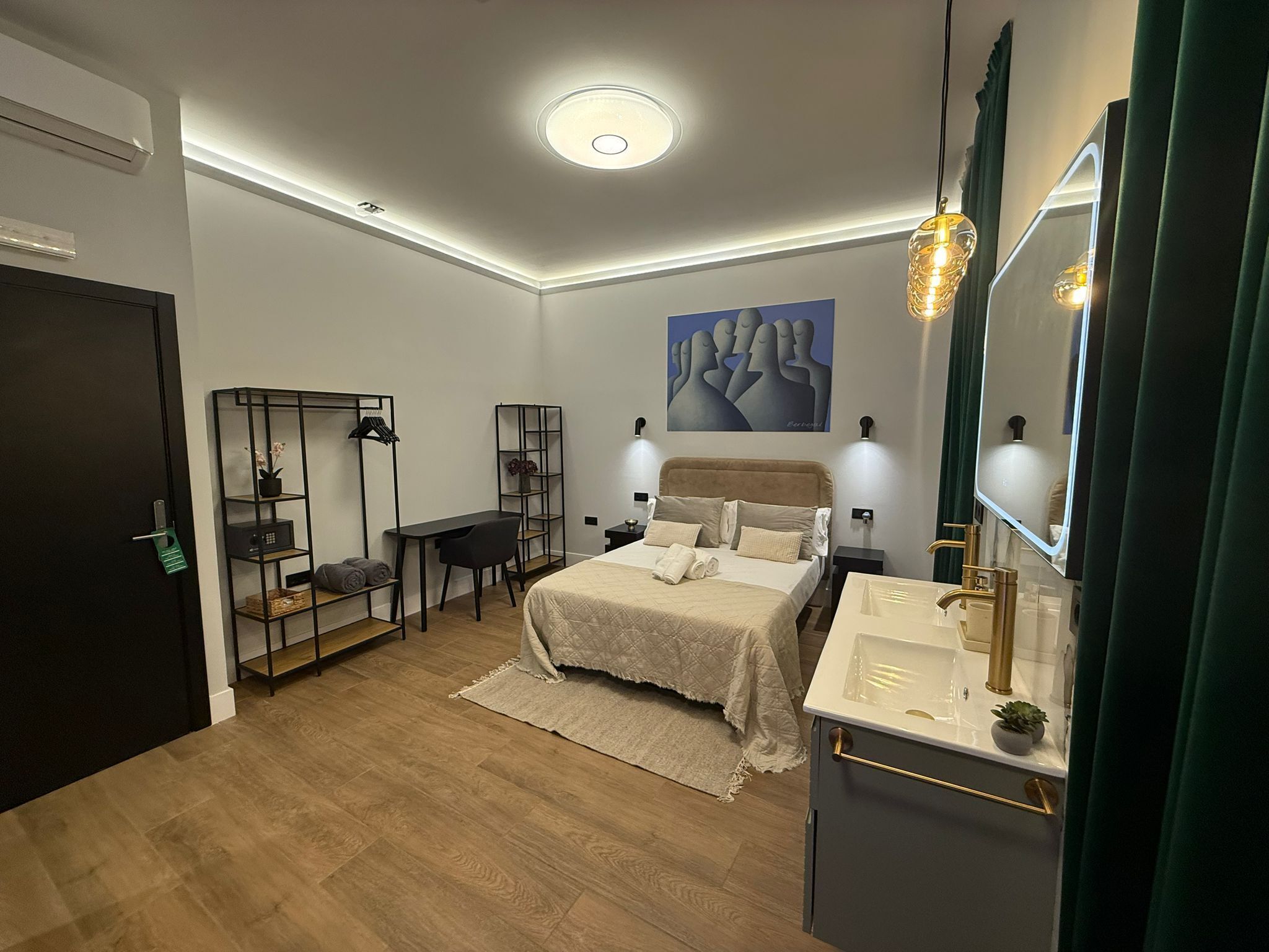 Un dormitorio moderno con cama, mesitas de noche, un escritorio y un espejo grande.