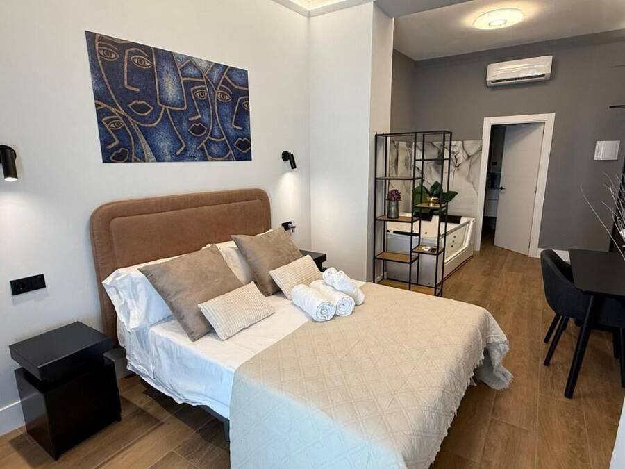 A modern bedroom with a large bed, a bedside table, a desk, and a chair.