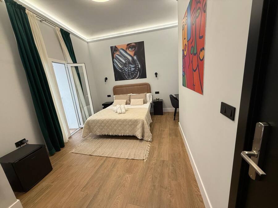 Un dormitorio moderno con cama, escritorio, silla y obras de arte en las paredes.