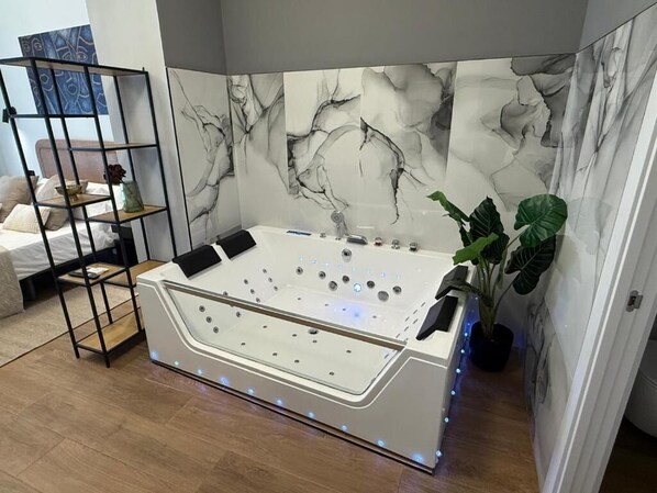 Une salle de bain moderne avec une baignoire sur pieds, un mur en marbre et une plante.