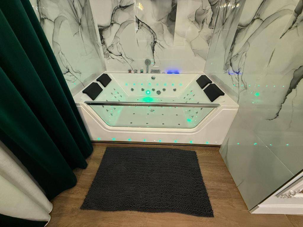 A modern bathroom with a glass-enclosed bathtub, a black towel, and a marble wall.