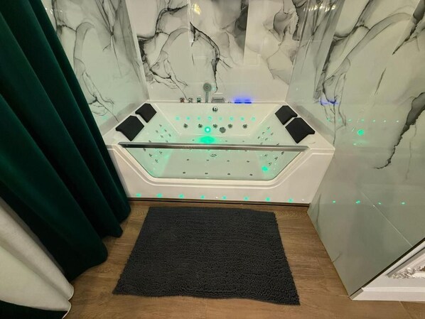 A modern bathroom with a glass-enclosed bathtub, a black towel, and a marble wall. - Hostal Ventura Luxury (Alicante)