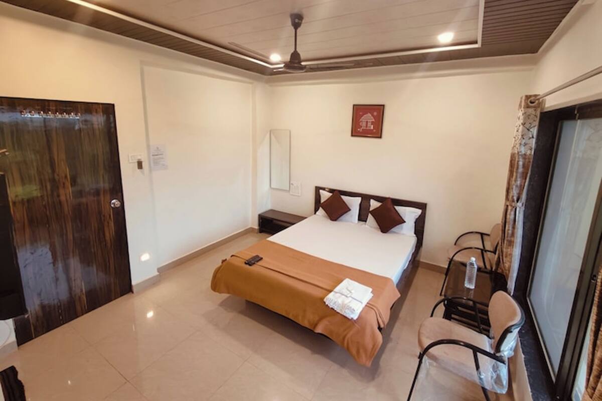 A hotel room with a bed, a desk, a chair, a ceiling fan, and a window with curtains.