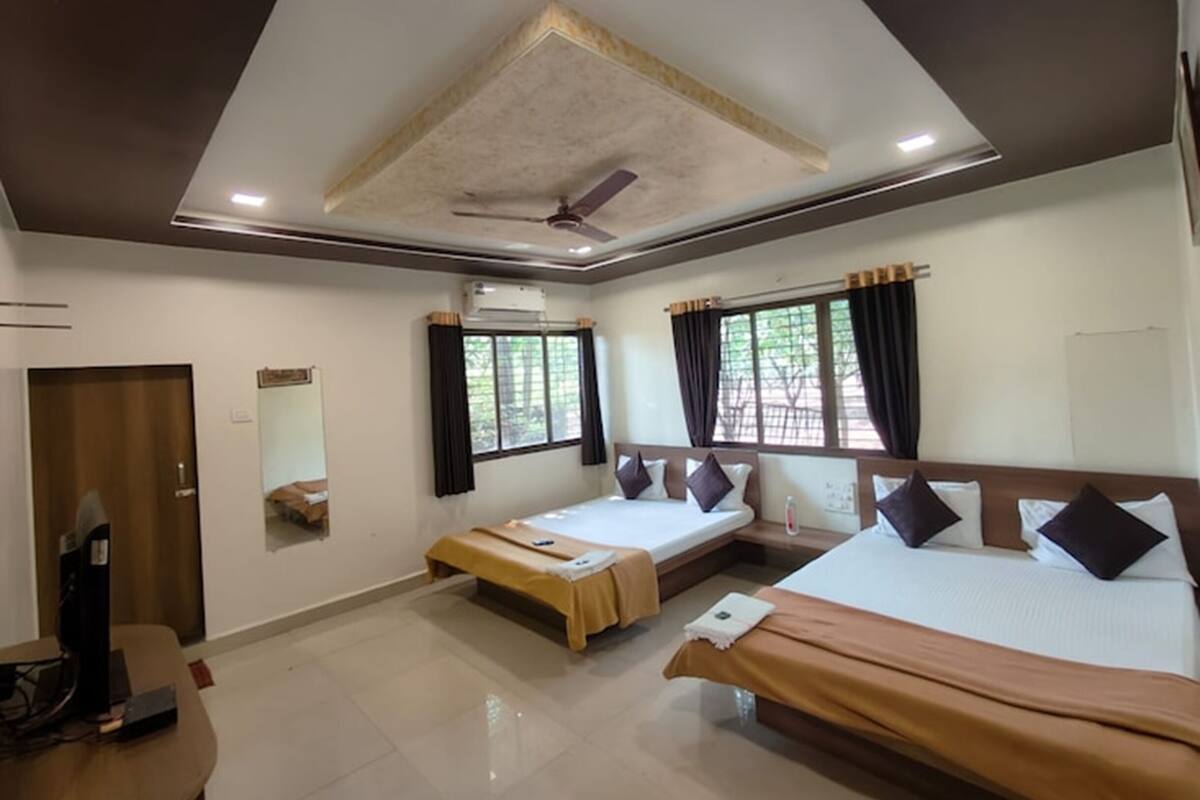 A hotel room with two beds, a desk, and a ceiling fan.