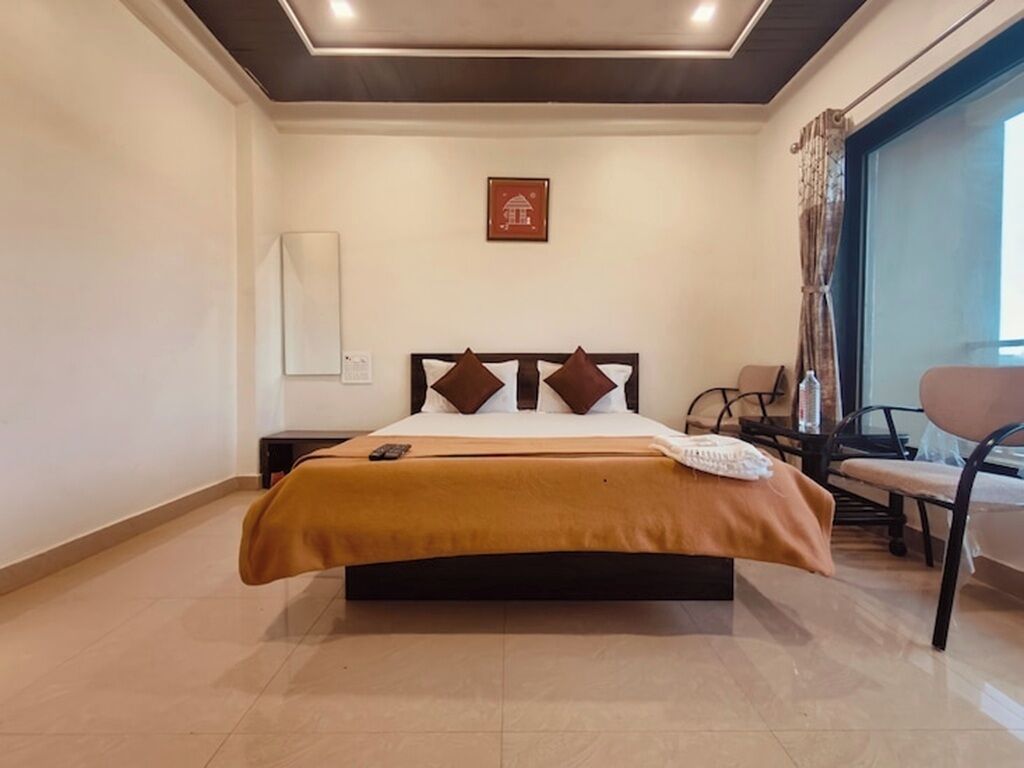 A hotel room with a bed, a desk, a chair, and a window.
