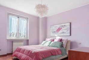 Una camera da letto con un letto, una finestra con tende, un termosifone e un'opera d'arte appesa al muro.