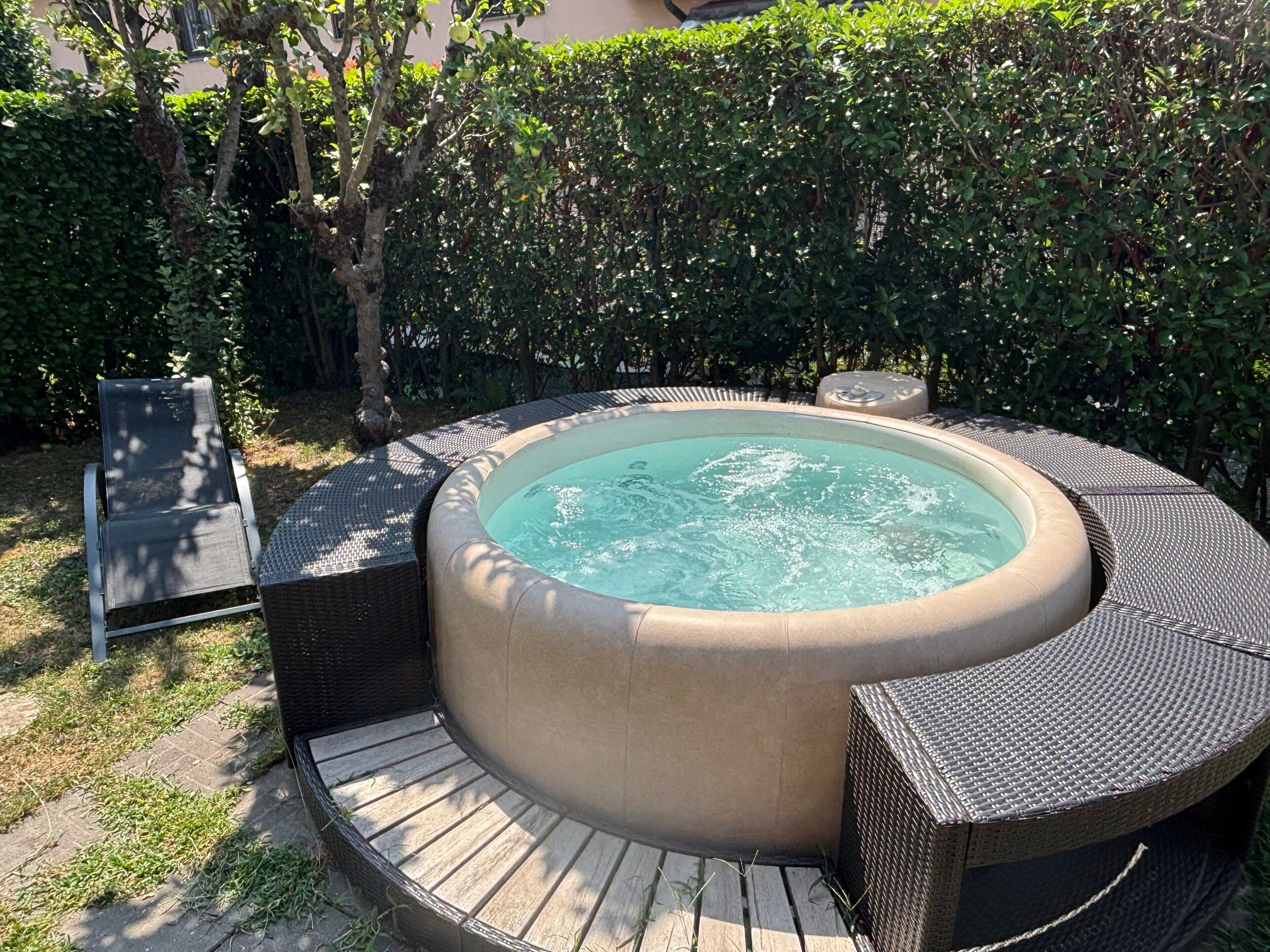 A hot tub with a circular design, surrounded by wicker furniture and a wooden deck.