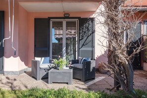 Un patio con mobili in vimini, una porta vetrata e una pianta in vaso.