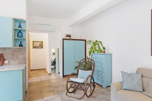 A room with a rocking chair, a light blue cabinet, a beige sofa, and a tiled floor. - Sorrento City Center Apartment with Balcony, Wi-Fi and Air Conditioning (Sorrento)