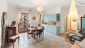 Amplia sala de estar con una mesa de comedor, sillas, un sofá y una cocina al fondo.