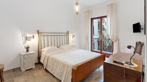 Un dormitorio con cama, mesita de noche, lámpara y vistas a un balcón.