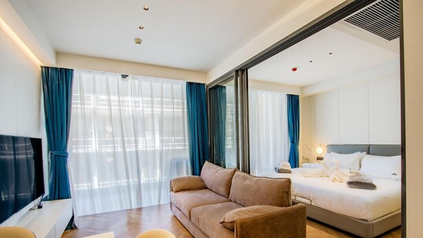 Ein Hotelzimmer mit einer Couch, einem Bett, einem Fernseher und einem Schreibtisch.