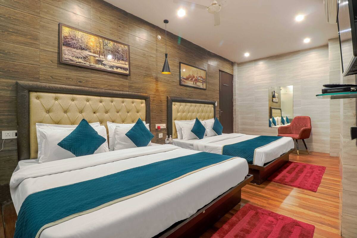Habitación de hotel con dos camas, paredes de paneles de madera y alfombra roja.