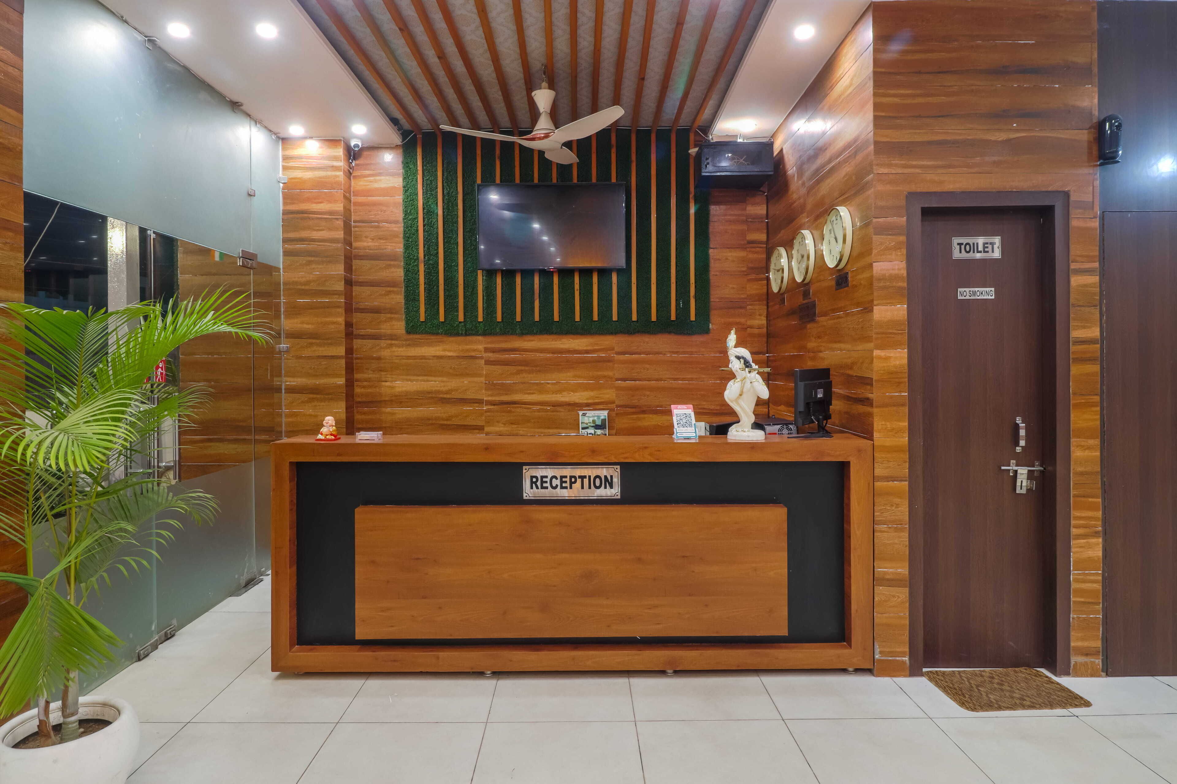 A reception desk with a "RECEPTION" sign, a television mounted on the wall, a ceiling fan, and a "TOILET" door with a "NO SMOKING" sign.