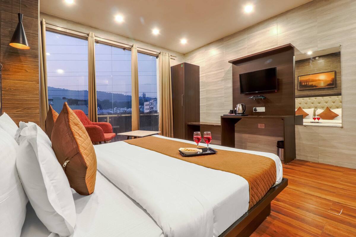 Habitación de hotel con una cama grande, televisión, escritorio pequeño y ventana con vistas a la ciudad.
