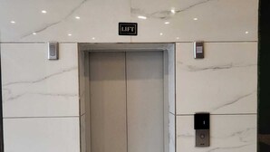An elevator with a 'LIFT' sign above it, set in a modern building with marble walls. - Hotel Siya Ram by AKC Hotels (Haridwar)