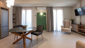 Un soggiorno moderno con un tavolo rotondo, due sedie, un televisore e una porta verde.