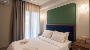 Una camera d'albergo con un letto, un comodino, una lampada a parete e una finestra con tende.