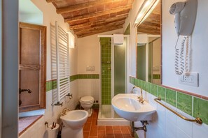 Une salle de bain avec un plafond en bois, une douche, deux lavabos et un sèche-cheveux fixé au mur.