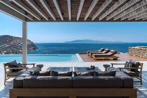 Un área de descanso al aire libre moderna con piscina, con vistas a un paisaje marino.