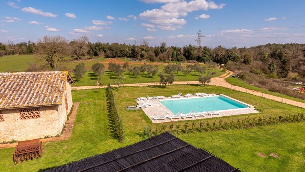 A swimming pool with lounge chairs, a stone building, and a grassy area with trees. - Camera Castello – Agriturismo la Taverna di Celsa with Shared Pool (Sovicille)