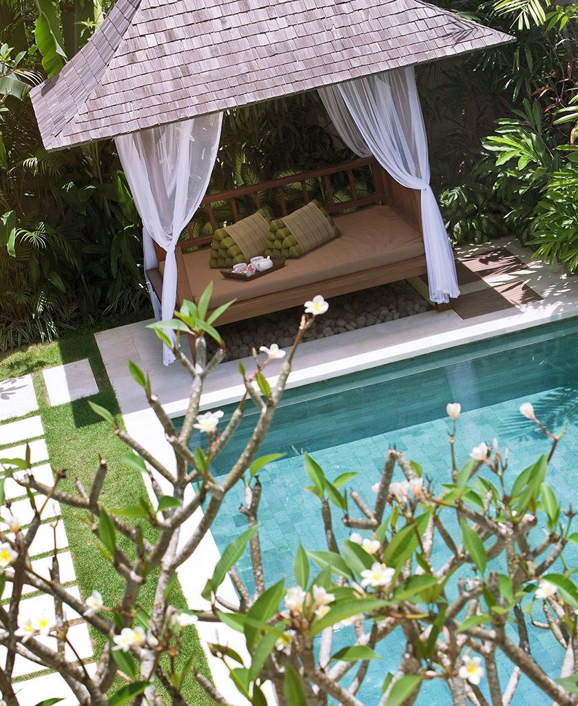 A poolside area with a wooden bench and a canopy.