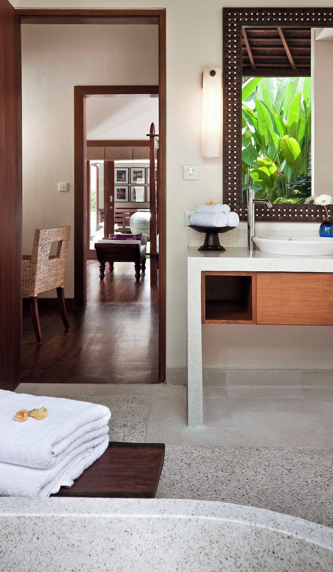 Ein Hotelzimmer mit Holztür, einem Badezimmer mit Waschbecken und Spiegel sowie Blick auf Grünflächen.