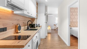 Cuina moderna amb armaris blancs, taulell de fusta i rentamàquines integrada.