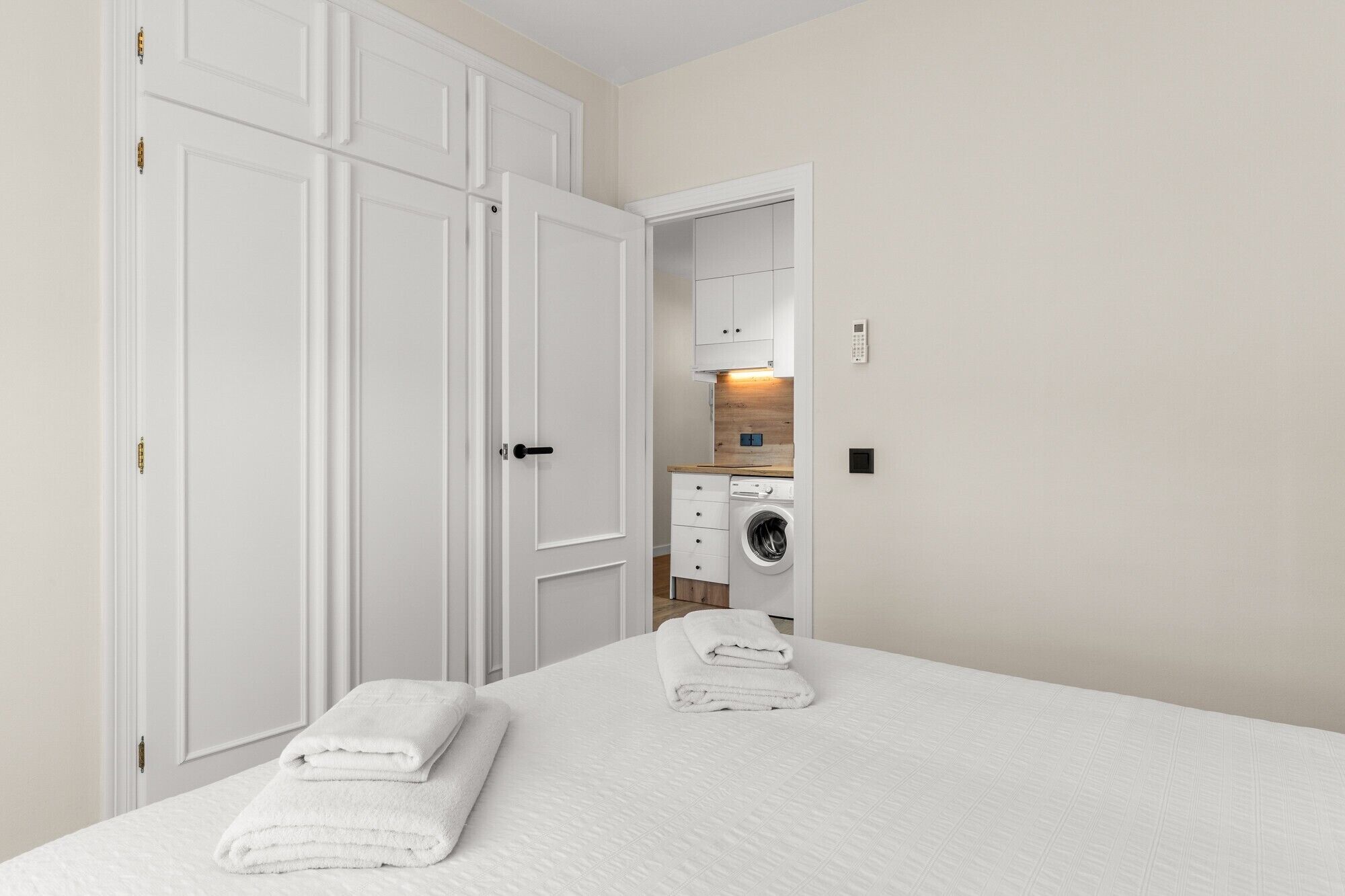 Une chambre à coucher avec un lit, deux serviettes blanches, un lave-linge et une armoire.